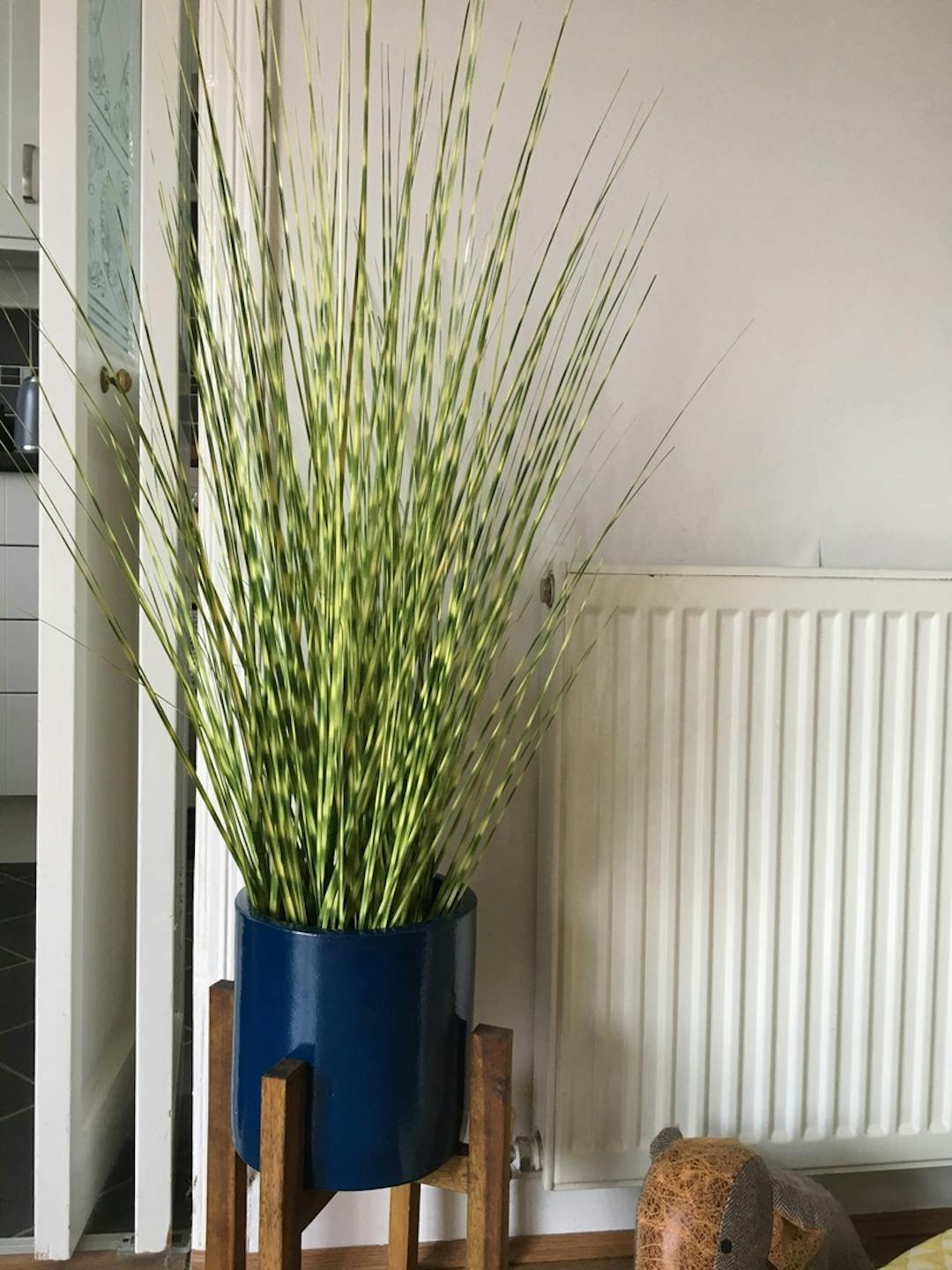 Artificial zebra grass in blue pot next to radiator