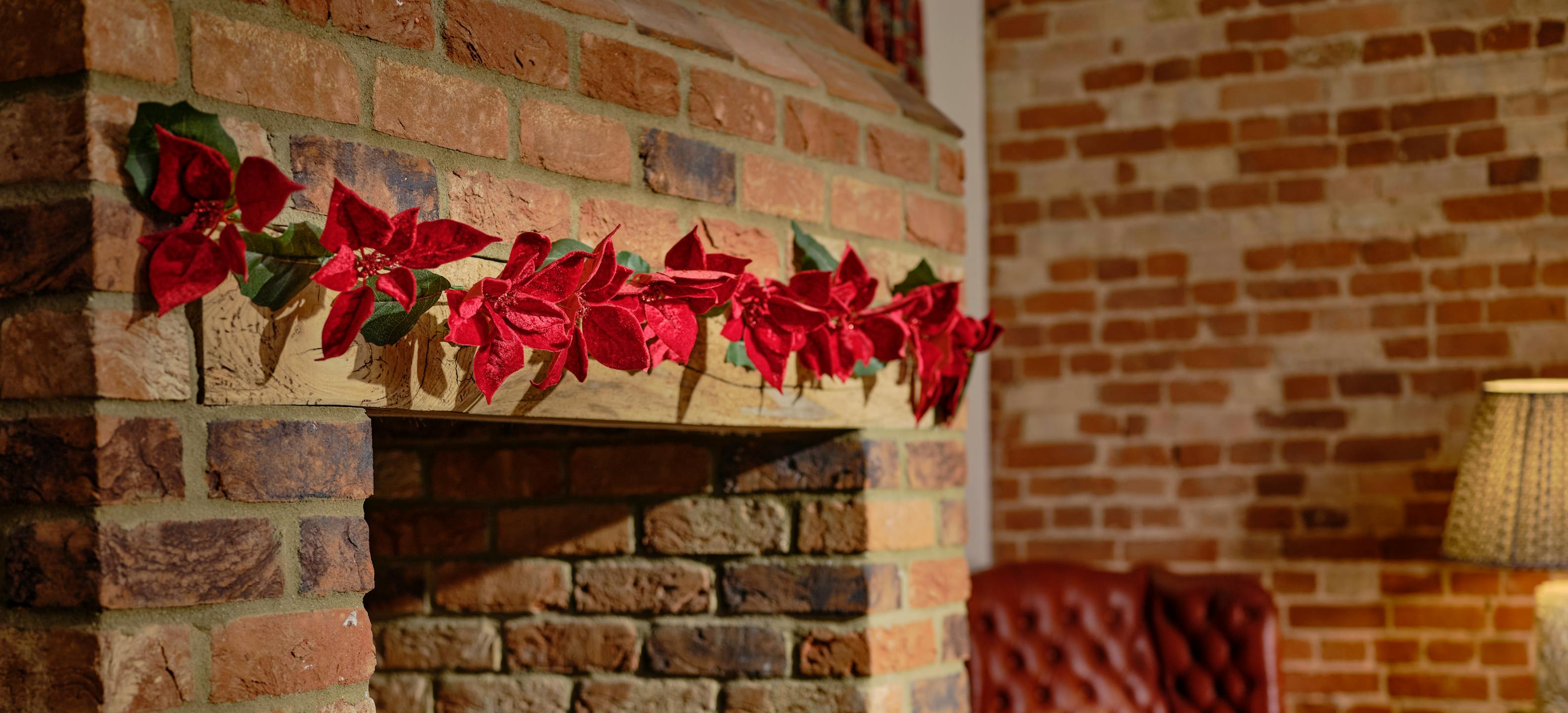 Artificial poinsettia garland over fireplace