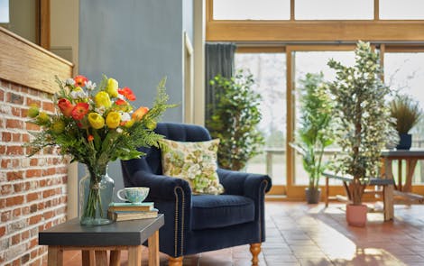Artificial spring bouquet in living room with blue armchair