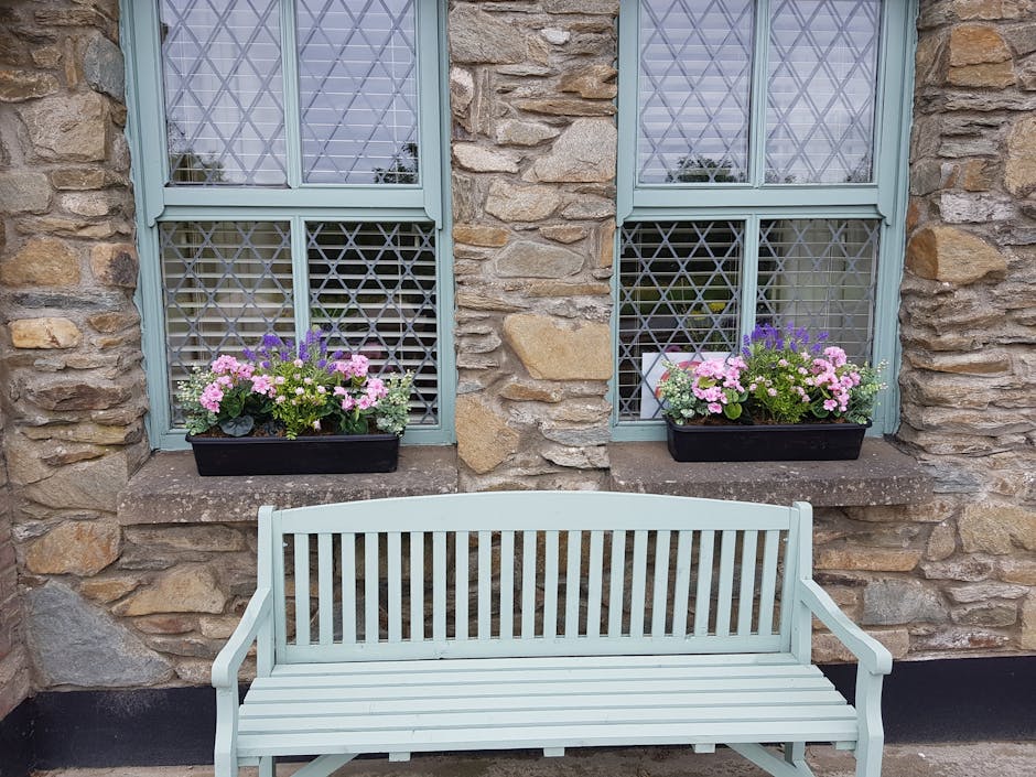 Artificial summer garden window boxes on window sill with bench