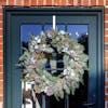 White Christmas luxury wreath hanging on green door by red-brick house