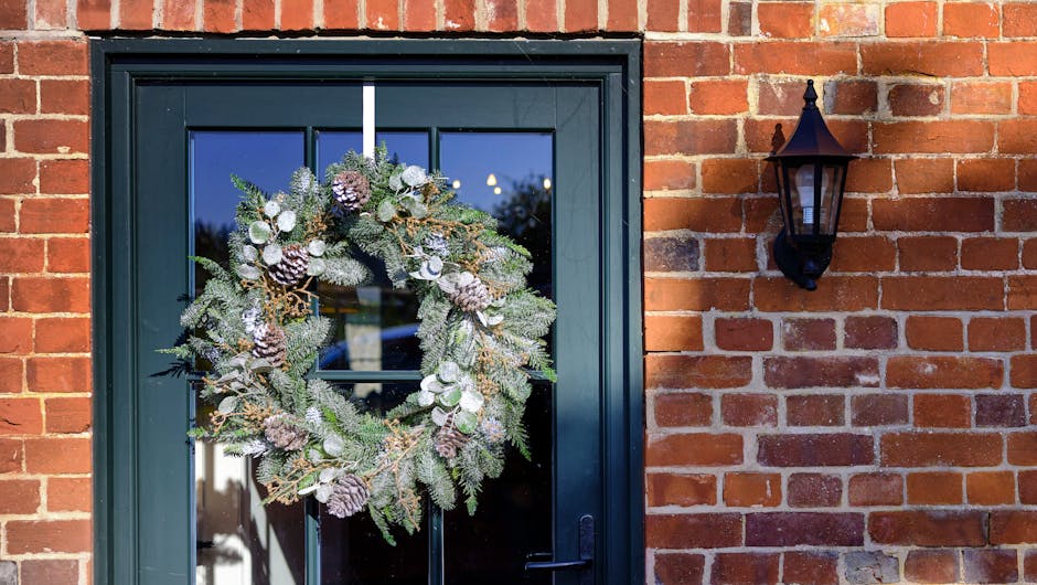 White Christmas luxury wreath hanging on green door by red-brick house