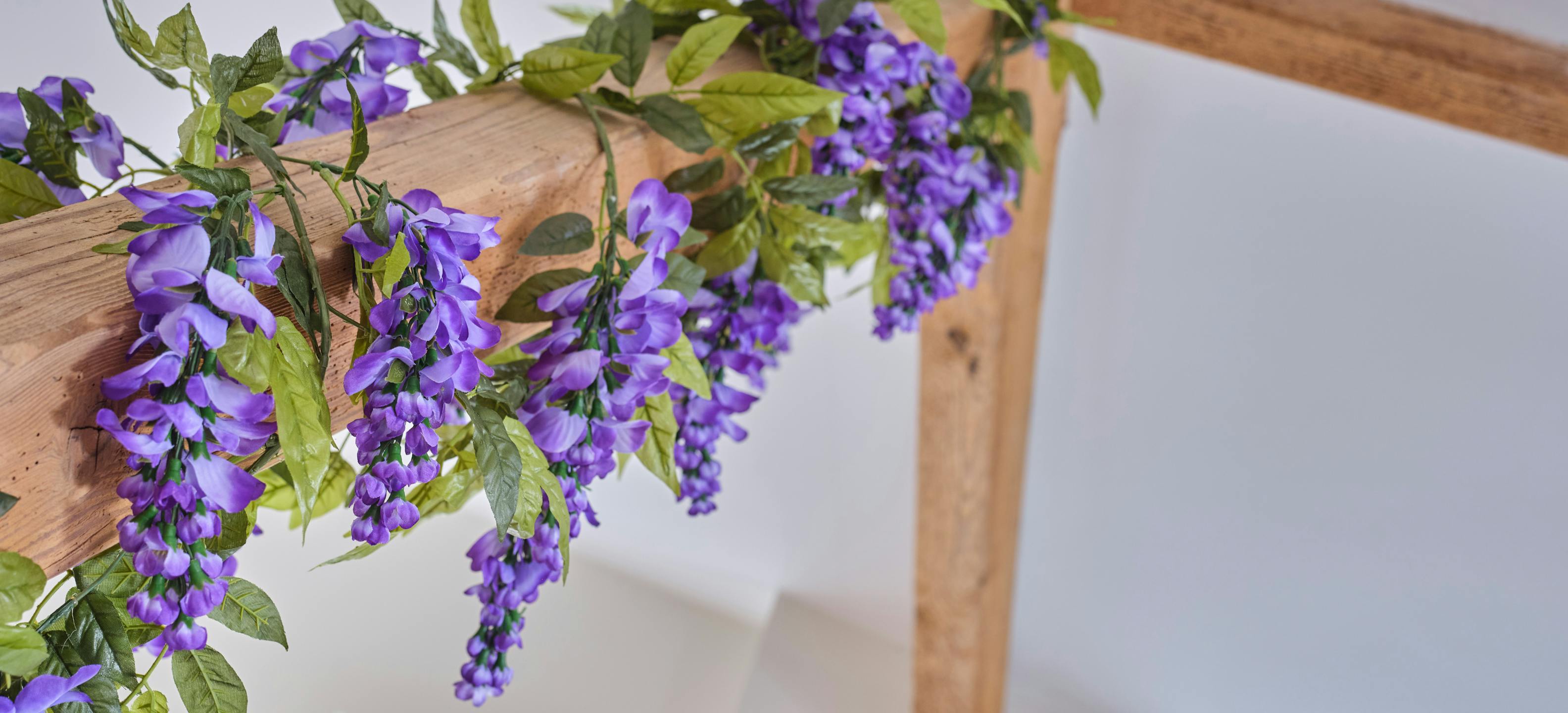 Purple artificial wisteria garland by Blooming Artificial wrapped around oak beam
