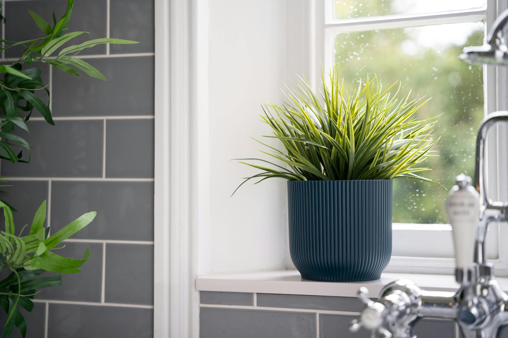 Artificial grass bush in navy planter in bathroom setting