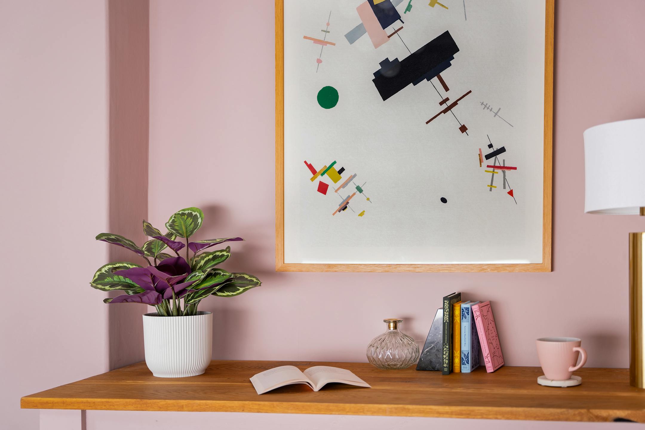 Artificial medallion calathea on wooden desk in pink office