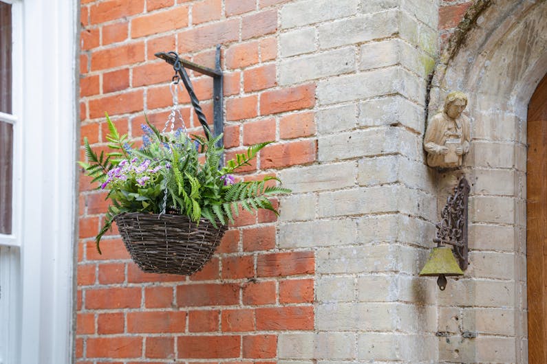 Artificial wild flower hanging basket outside red brick house