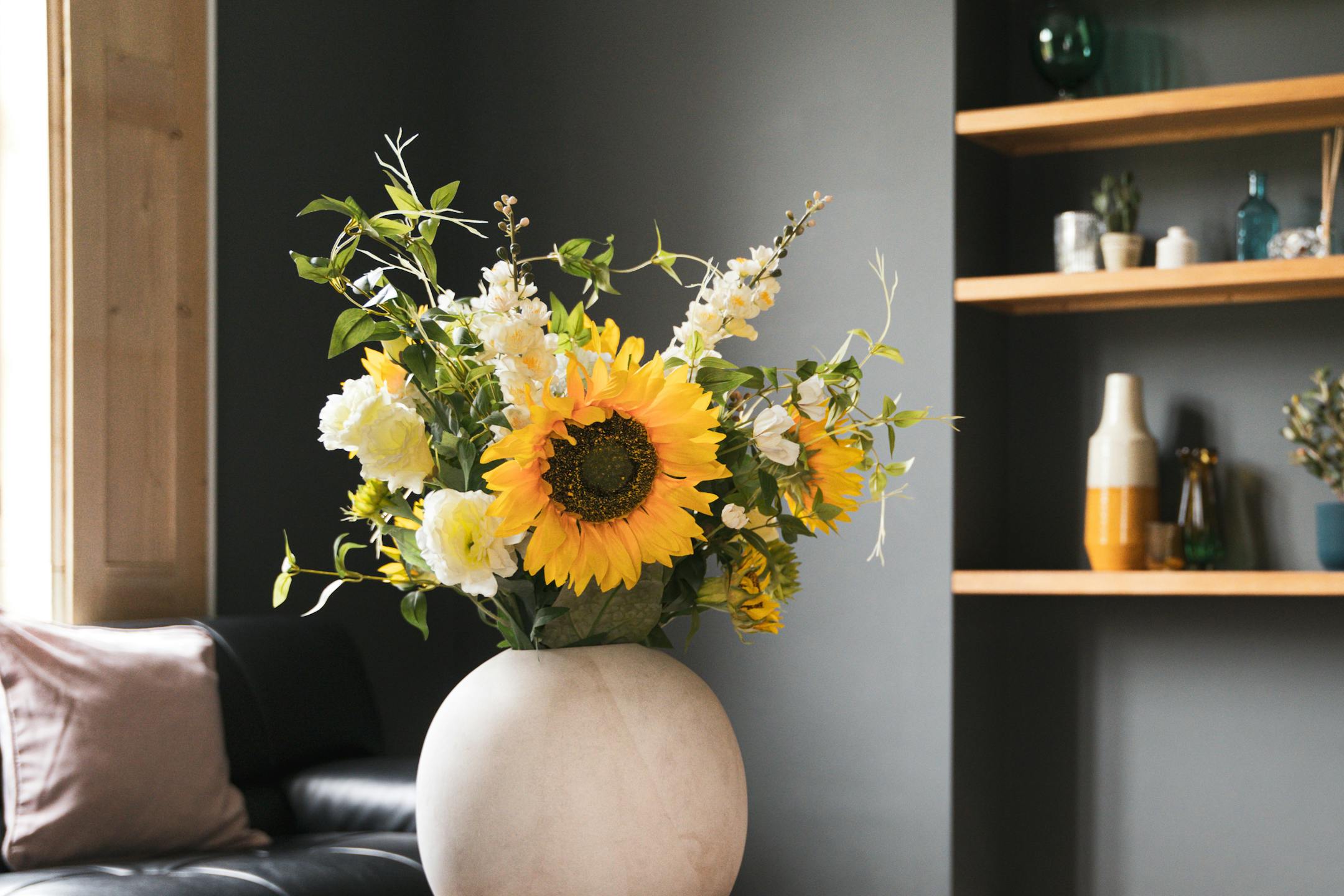 Artificial yellow lazy days sunflower bouquet in cement vase in blue interior
